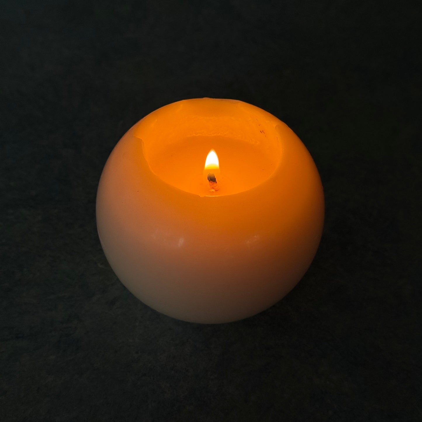 Minimalist burning sculptural sphere candle in ivory wax